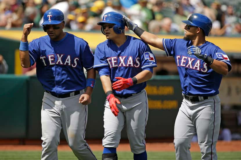 Texas Rangers' Shin-Soo Choo, center, of South Korea, is greeted by teammates Carlos...