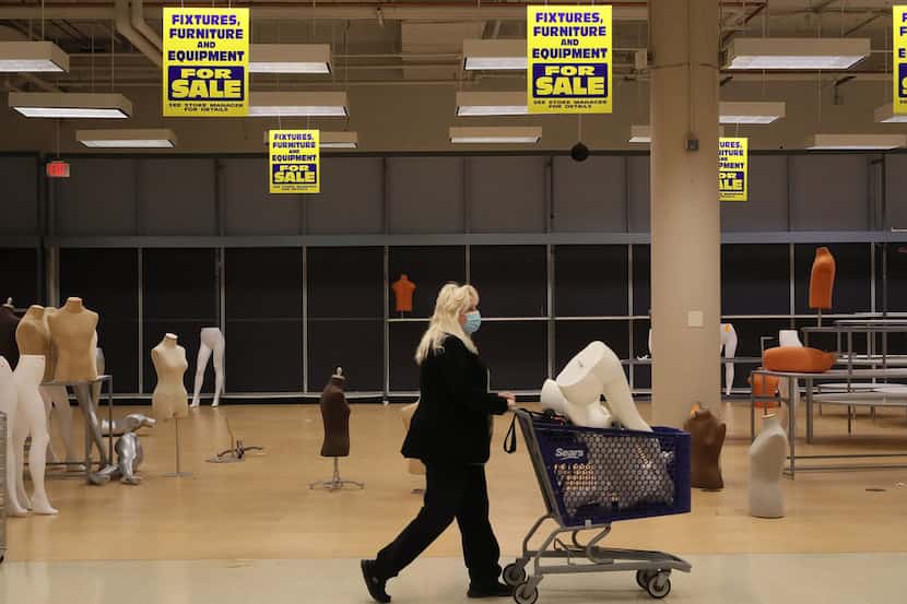 Patti Naleck pushes a cart filled with a mannequin through the Sears store in Woodfield Mall...