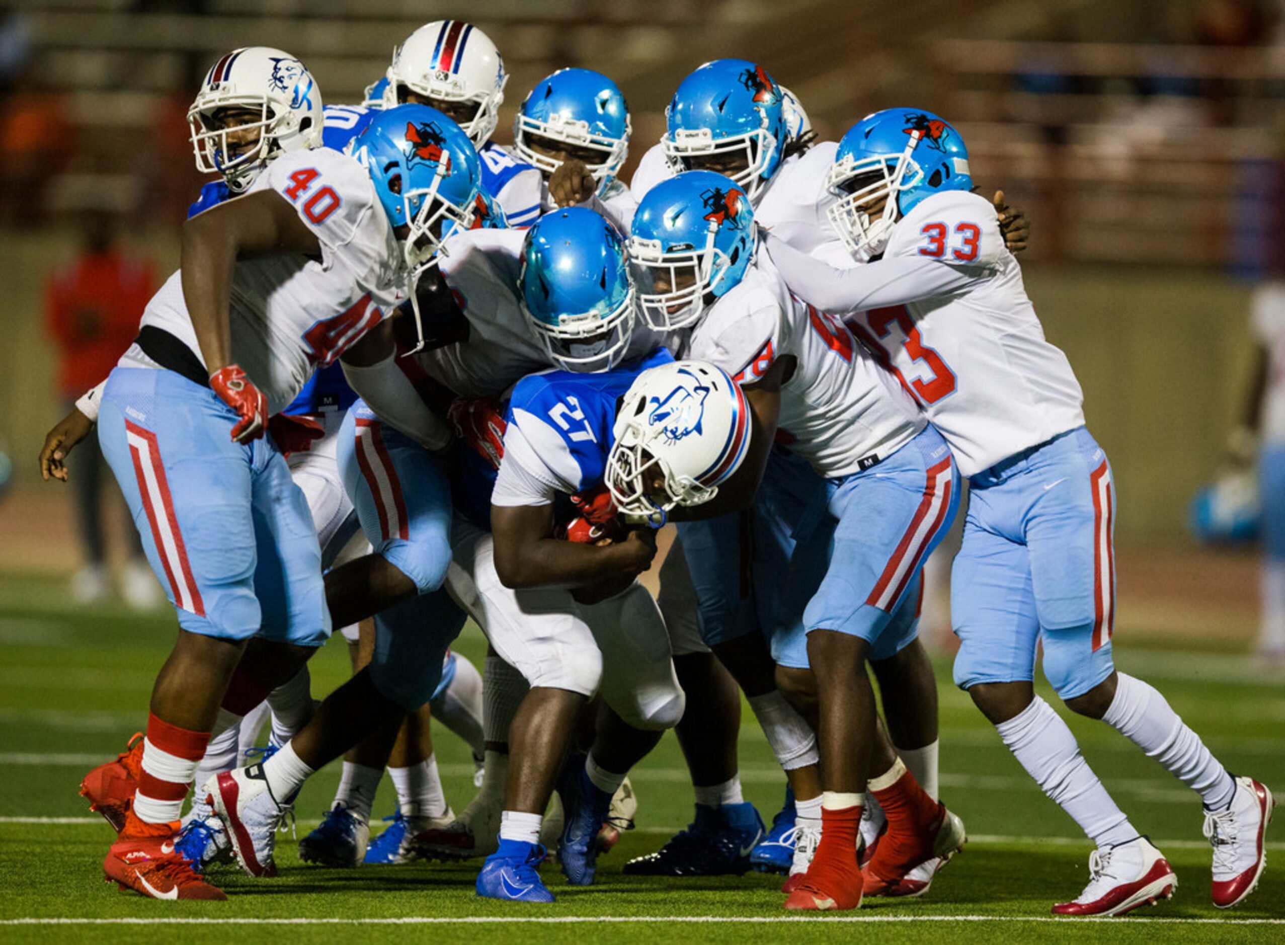 Duncanville running back Couvarris Butler (27) is tackled by the Skyline defensive line...