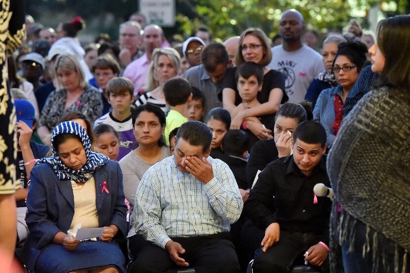 Efrain Gomez wipes his eyes while seated next to his wife, Balvina, during a vigil for their...