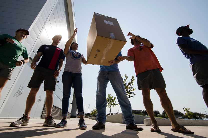 In Wednesday, Sept. 6, 2017, file photo, volunteers move boxes of shoes donated by Mythiquer...