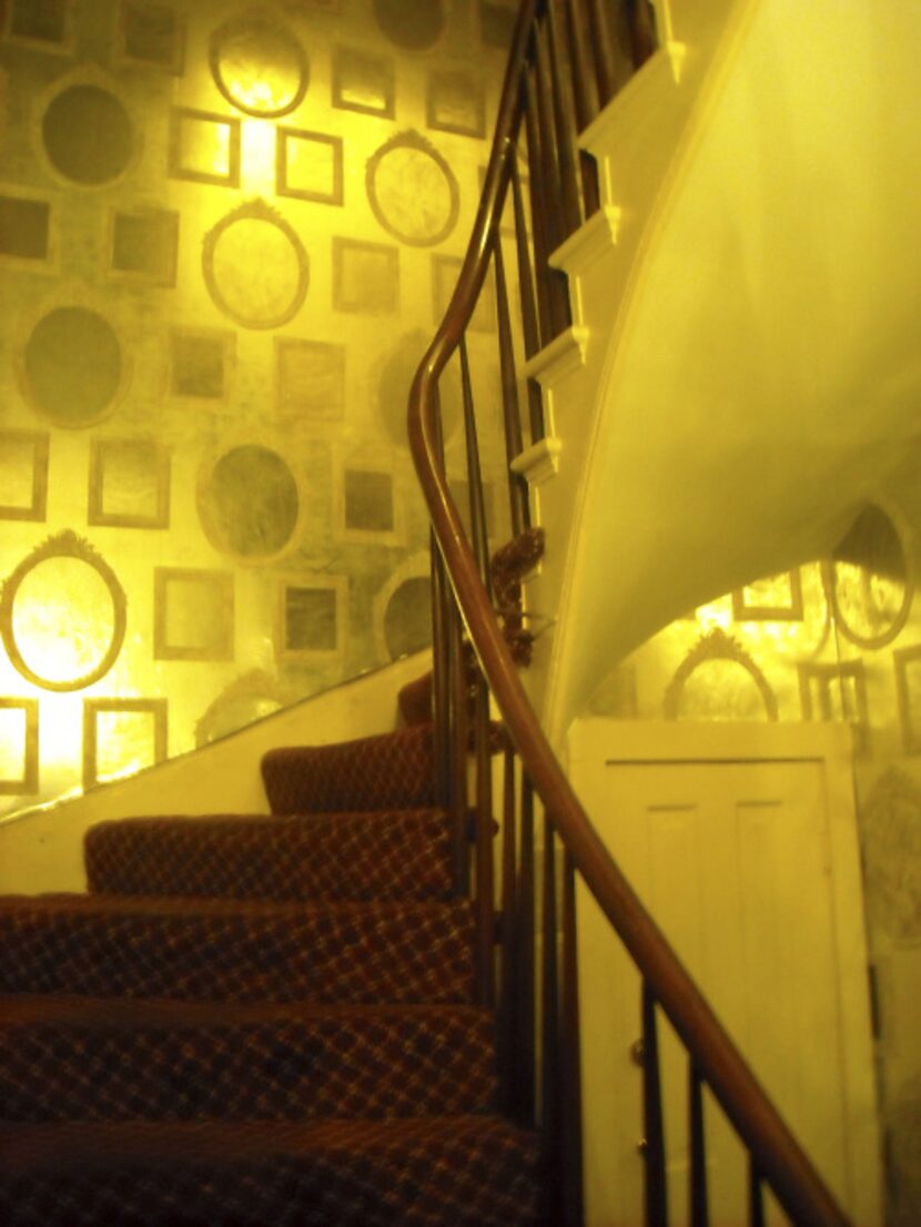 A stairwell and hallway at Arnaud's Restaurant have wallpaper with faux-mirror designs....