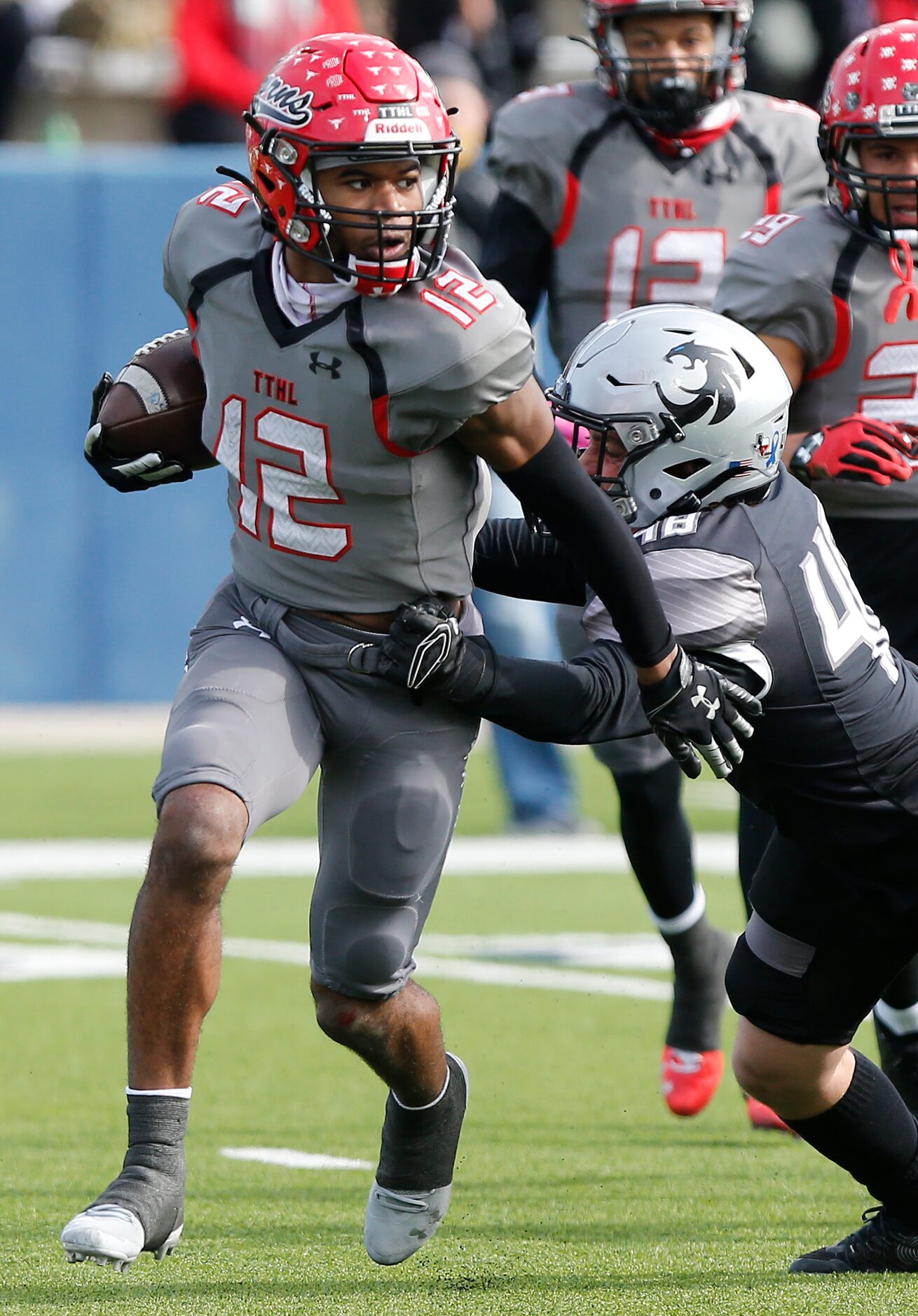 Cedar Hill High School wide receiver Brian Rainey (12) runs out of the grasp of Denton Guyer...