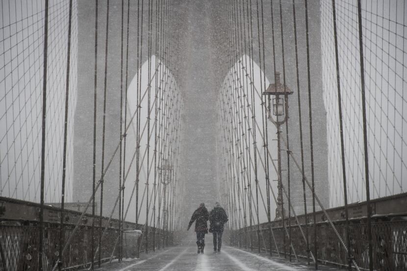 NEW YORK, NY: People walk on the Brooklyn Bridge during a winter storm, January 4, 2018 in...