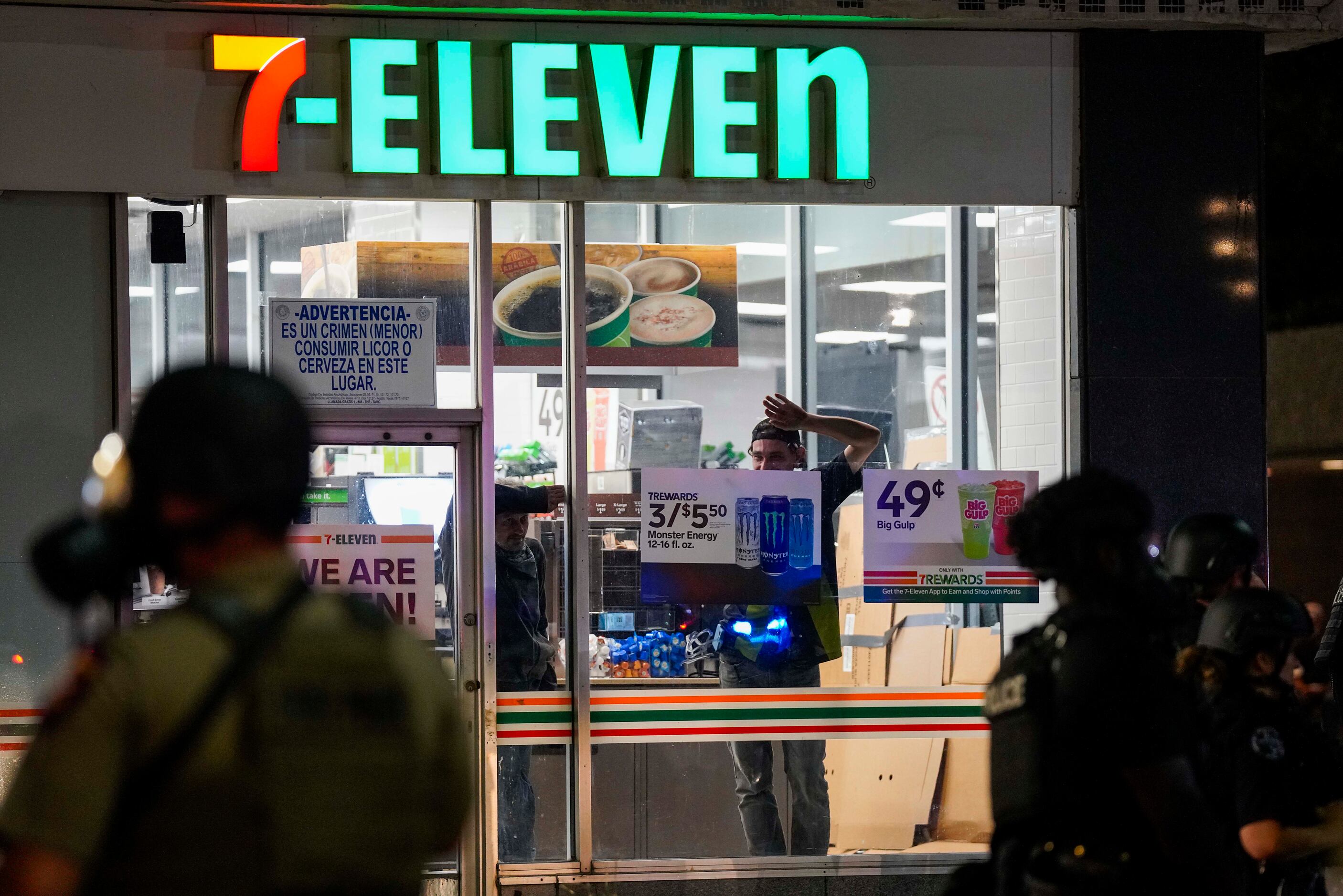 Men look out the windows of the 7-11 store on Elm Street at Ervay as Dallas police and ...