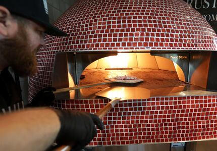 Micah Long makes a fig and prosciutto pizza at Rustic Flats, a food stand inside Urban8 in...