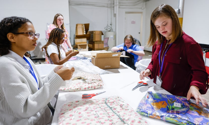 Volunteers Caitlyn Johnson (left) and Casey O’Brien cut tags off dresses at Avara’s...