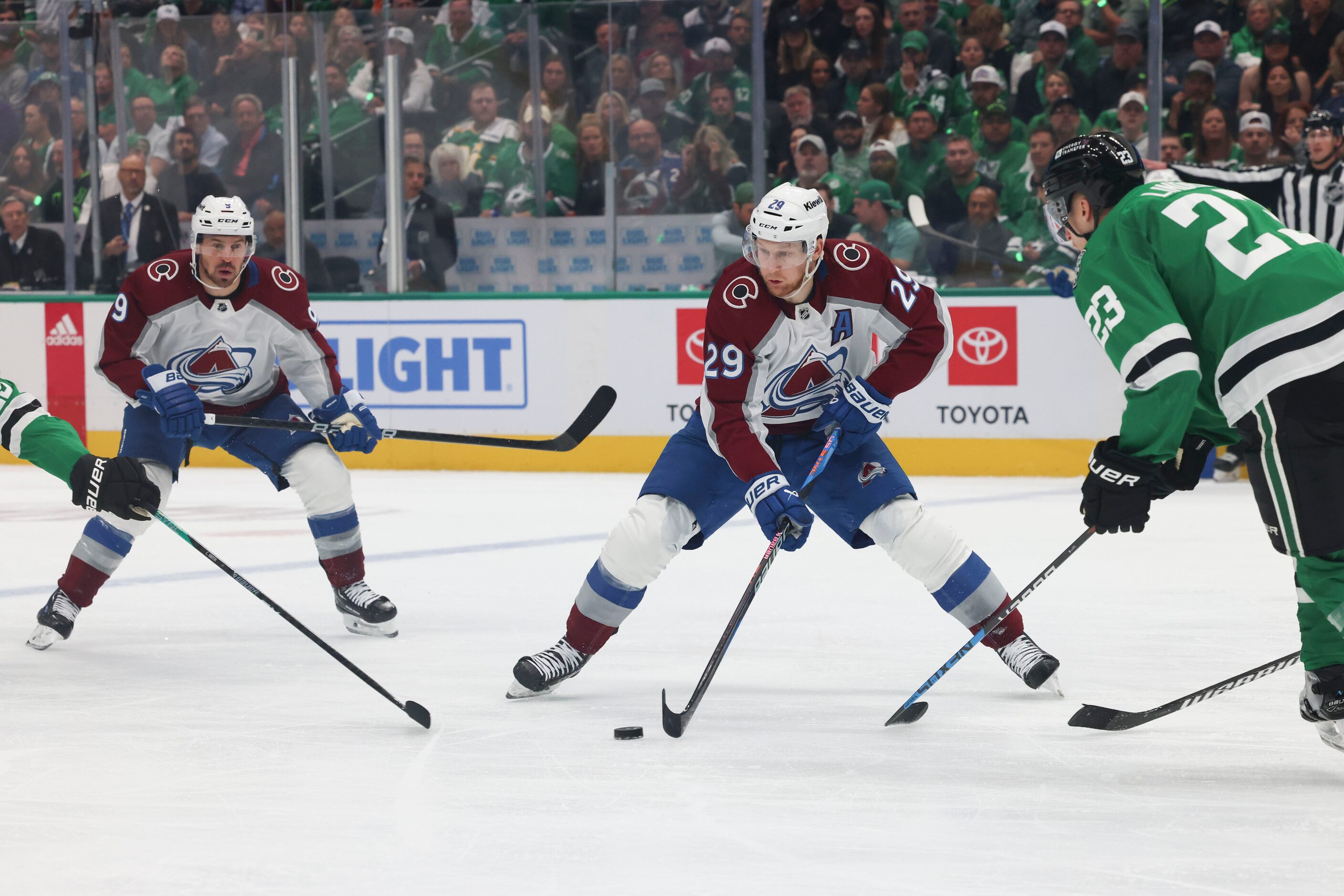 Colorado Avalanche center Nathan MacKinnon (center) controls the puck against Dallas Stars...