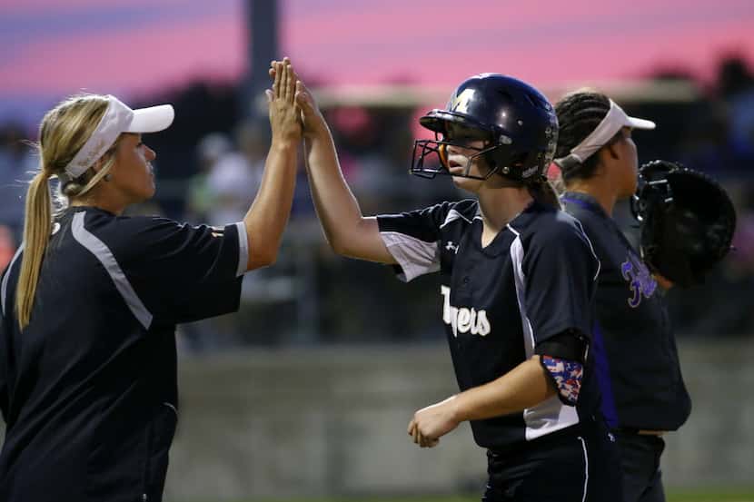 Mansfield batter Paxton Scheurer (right) is congratulated by first base coach Neely Trotter...