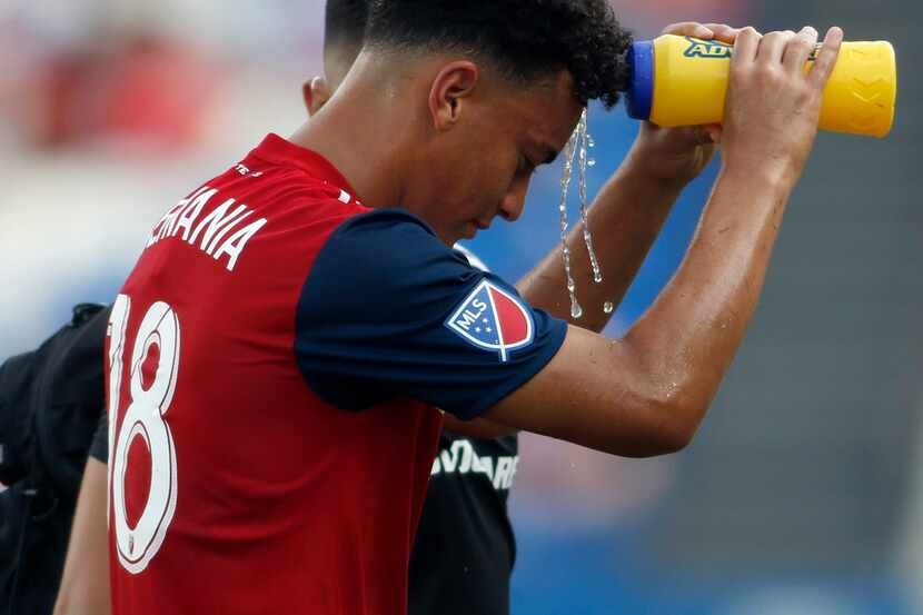 FC Dallas midfielder Brandon Servania (18) tries to cool himself as he leaves the field with...