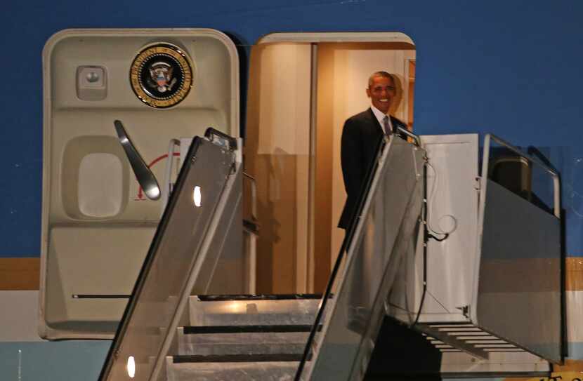 President Barack Obama smiles from onboard Air Force One as he leaves after a trip to Dallas