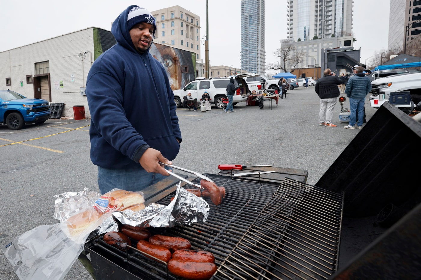 Dallas Cowboys fan Ray Becton of Charlotte cooks sausages while tailgating before an NFL...