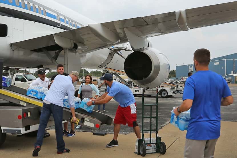Dallas Mavericks player J.J. Barea (right) helps transfer supplies from a trailer to an...