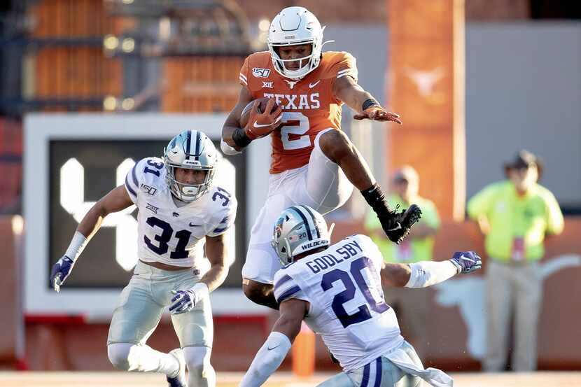 Texas running back Roschon Johnson (2) hurdles Kansas State defensive back Denzel Goolsby...