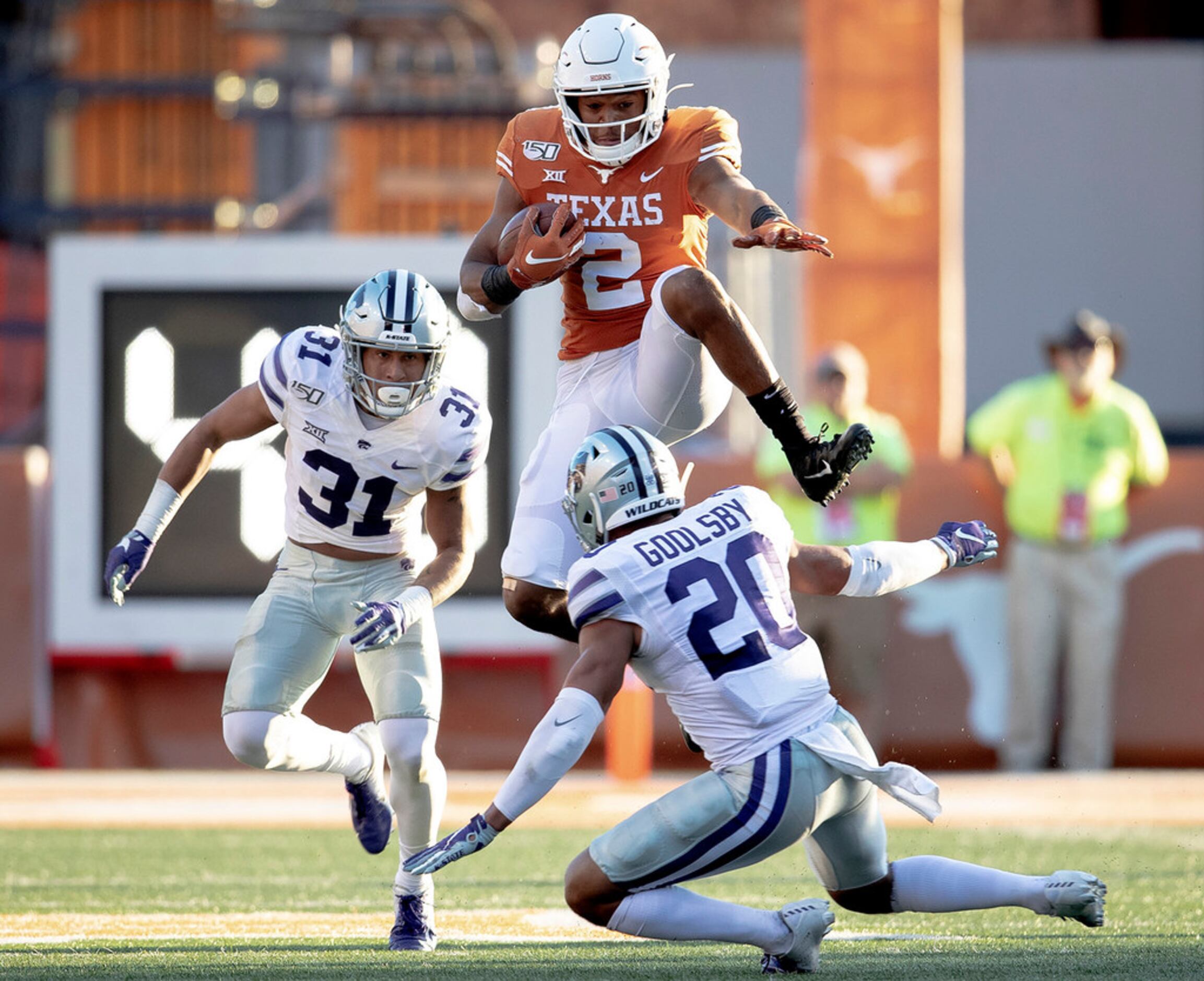 Texas running back Roschon Johnson (2) hurdles Kansas State defensive back Denzel Goolsby...