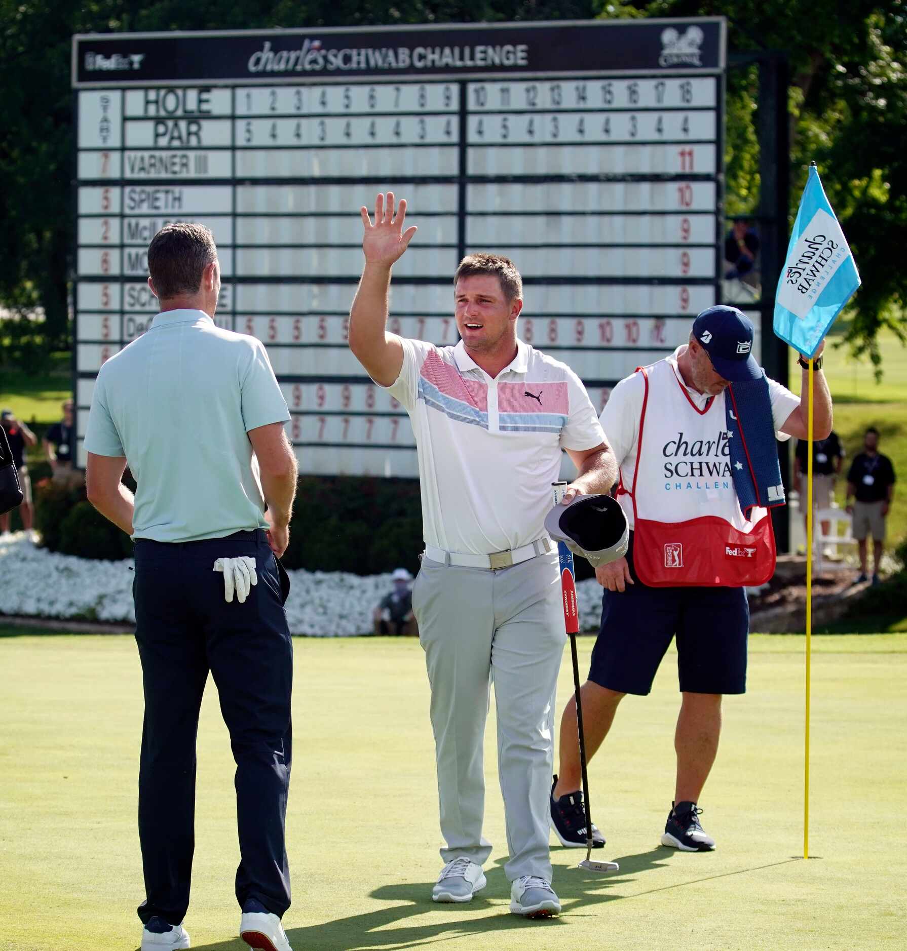 PGA Tour golfer Bryson DeChambeau gives an air high-five to playing partner Justin Rose...