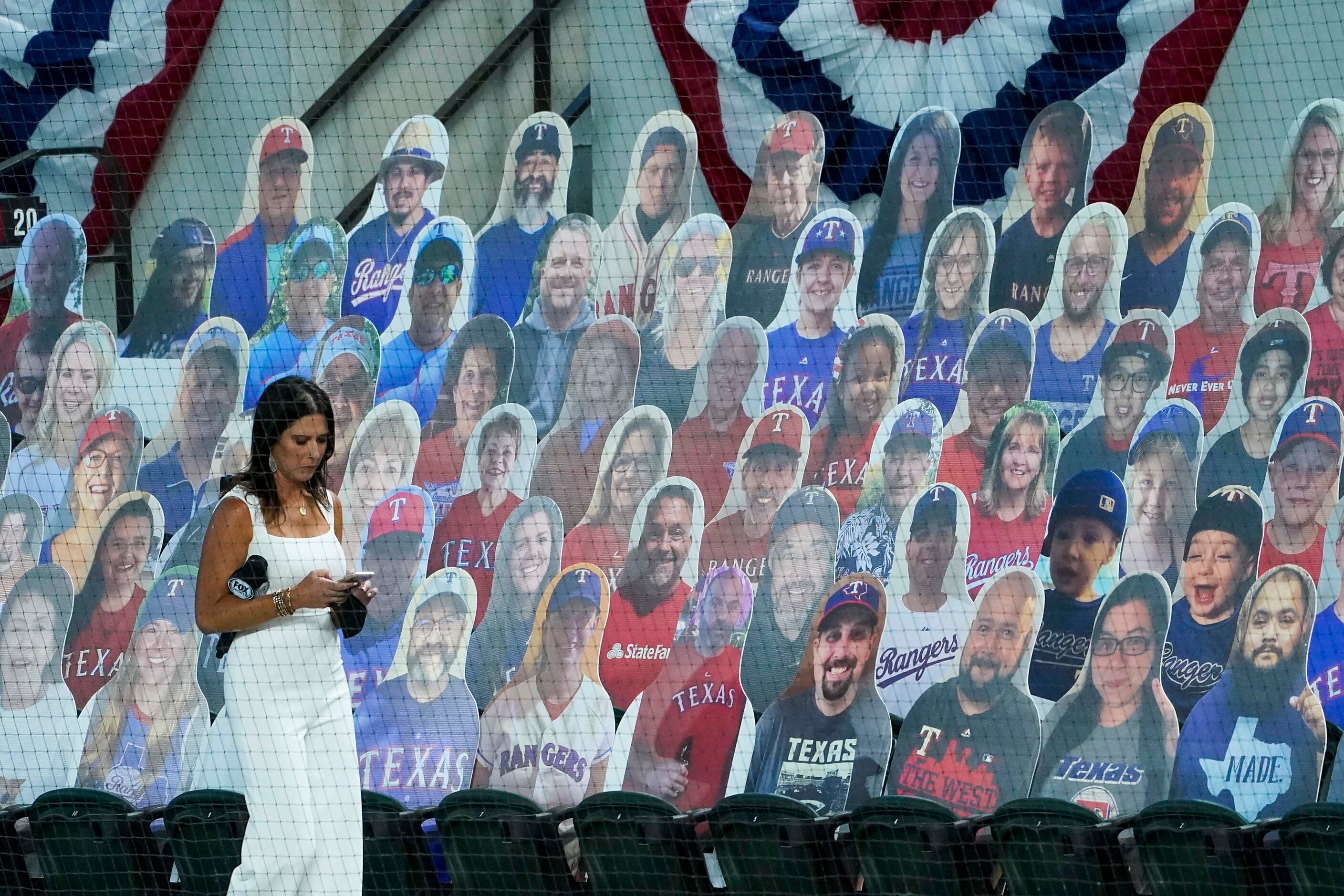 Fox Sports Southwest reporter Emily Jones walks among cutout photos of fans, sold as ÒDoppel...
