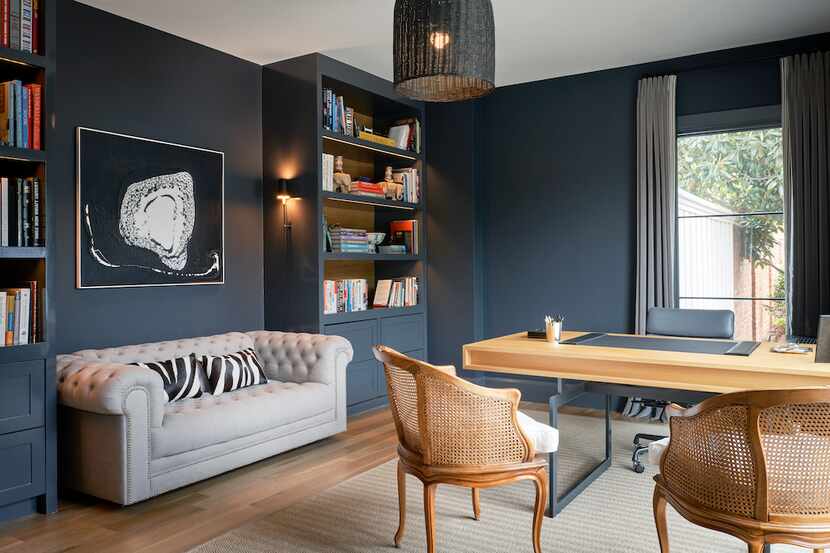 Study with gray-blue walls and a light sofa nestled between two bookshelves and sconce lighting