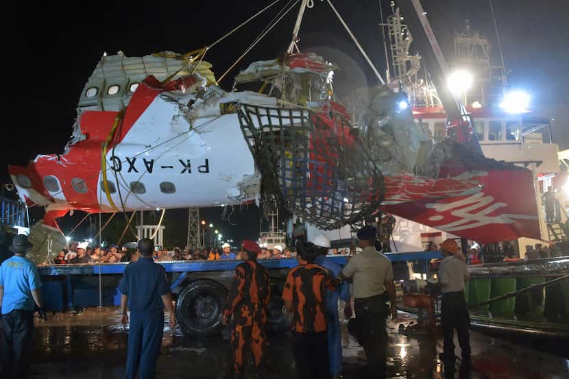 Indonesian personnel unload a section of recovered wreckage belonging to AirAsia flight...