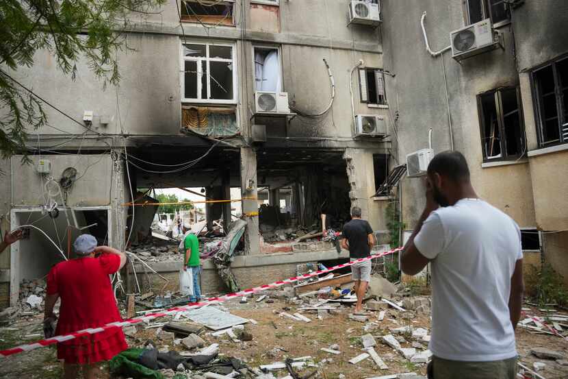 Varios israelíes inspeccionan un edificio residencial dañado que se vio alcanzado por un...