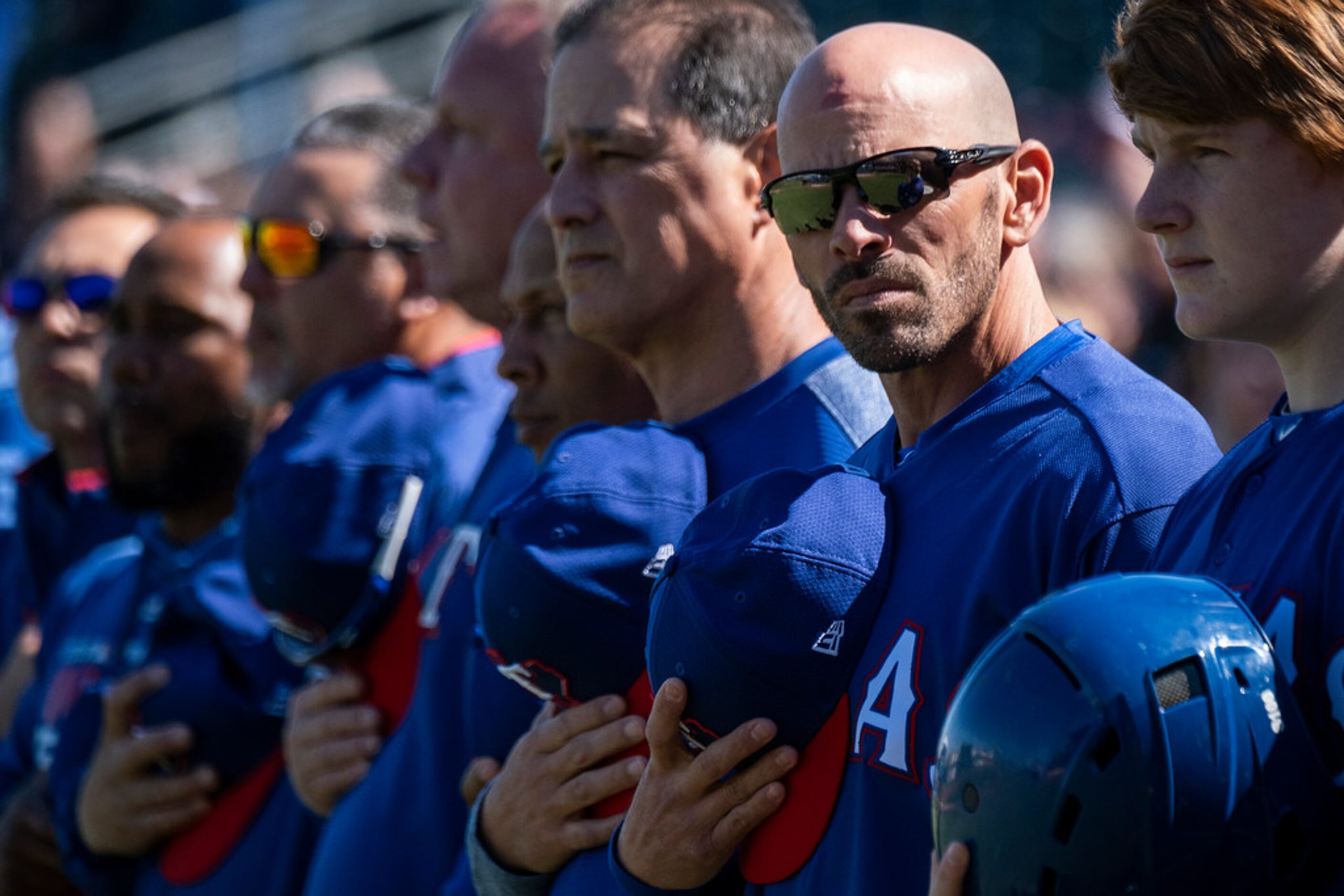 Texas Rangers manager Chris Woodward stands for the national anthem before a spring training...