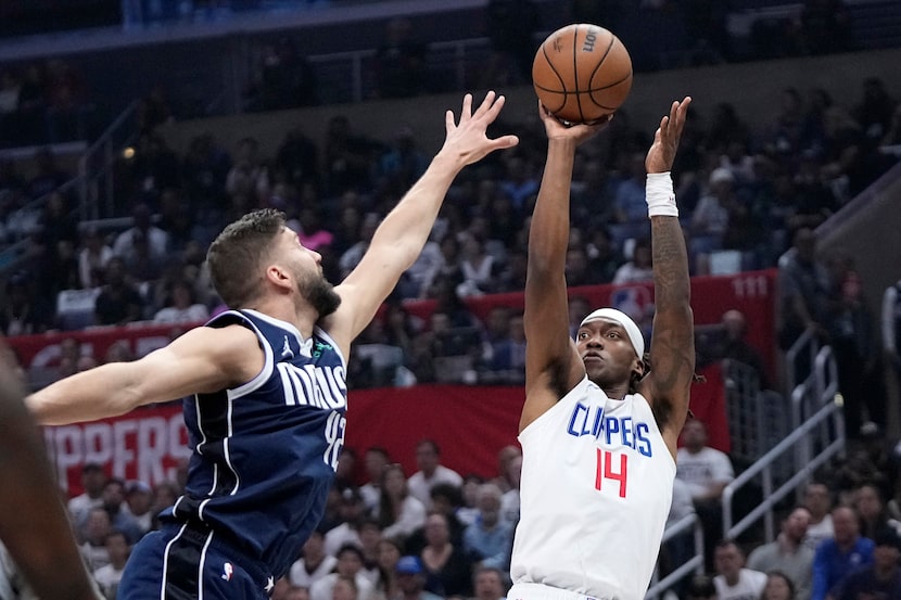 Los Angeles Clippers guard Terance Mann, right, shoots as Dallas Mavericks forward Maxi...