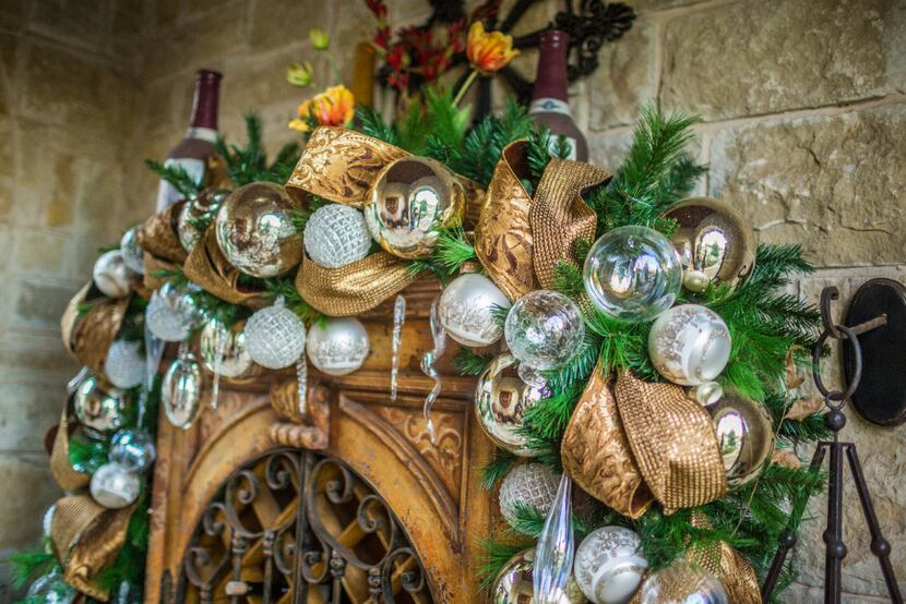 A garland with white and gold ornaments adorns a wine closet tucked under a covered porch.