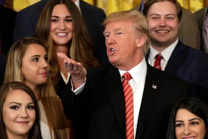 US President Donald Trump gestures during a group photo with outgoing interns at the White...