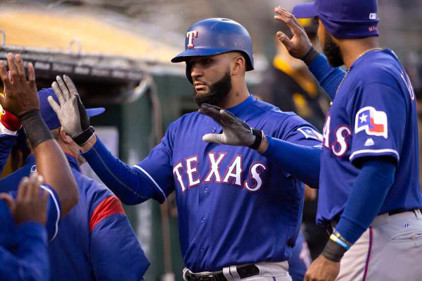 Texas Rangers right fielder Nomar Mazara, center, is congratulated by his teammates after...