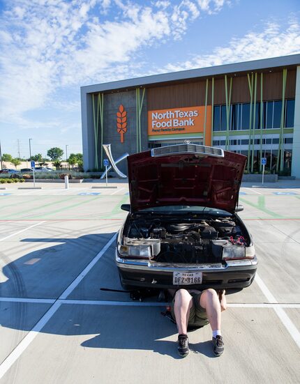 Elise Earnhart Bigony repairs her stalled car after donating food at North Texas Food Bank...