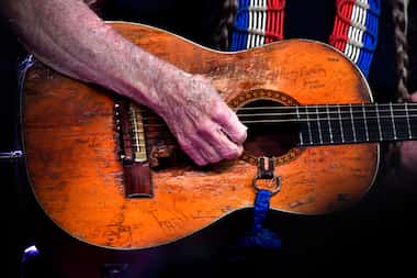 Willie Nelson strums his well-worn guitar, Trigger, during his set at the Outlaws & Legends...