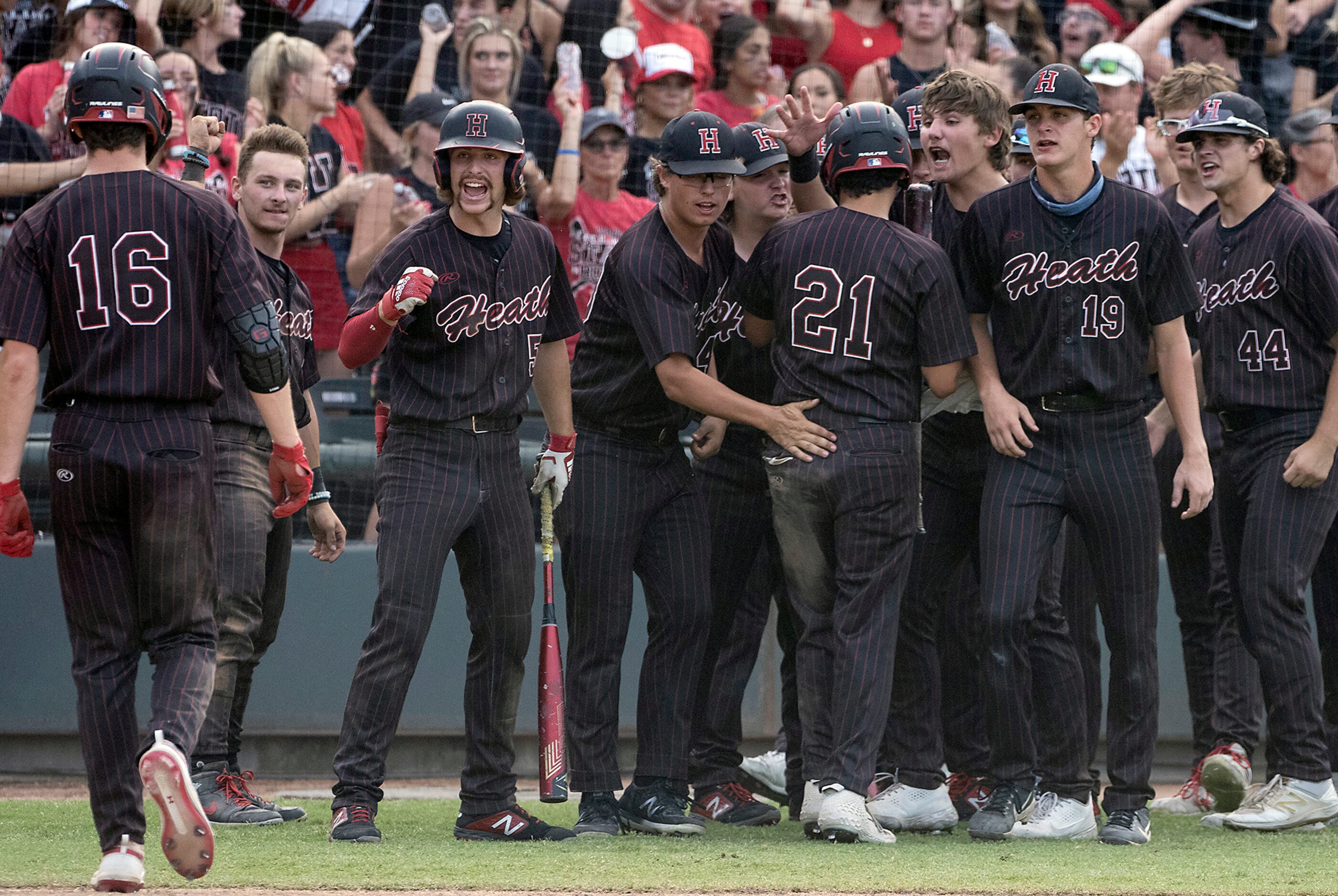 Rockwall-Heath Caden Fiveash, (16), walks to the dugout after scoring Zach Rike, (21), for...