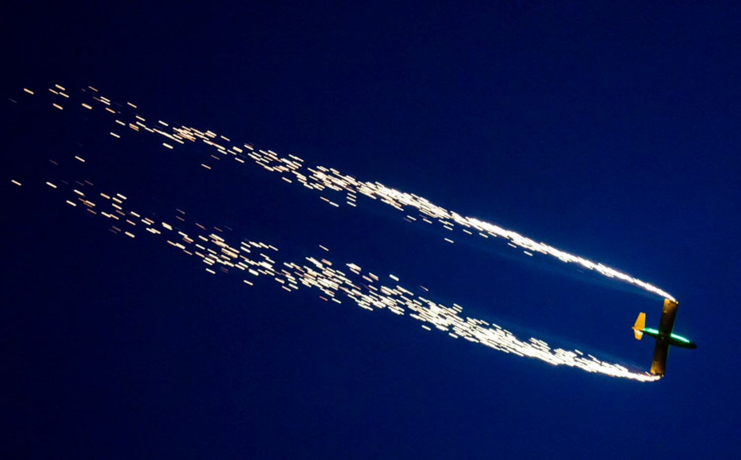 An airplane trails sparks as part of an airshow during the Addison Kaboom Town! festival and...