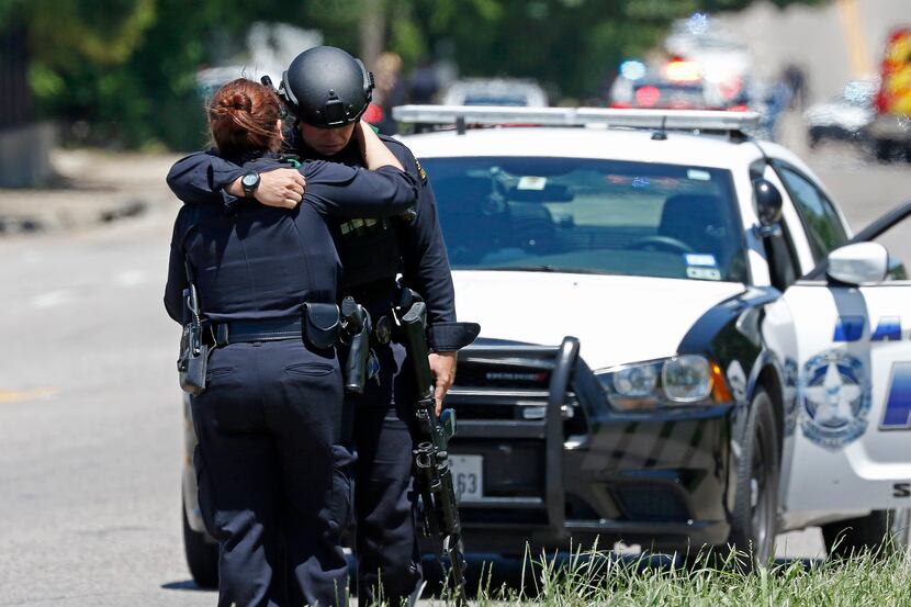 Two Dallas police officers comforted each other at the scene Monday where a Dallas...