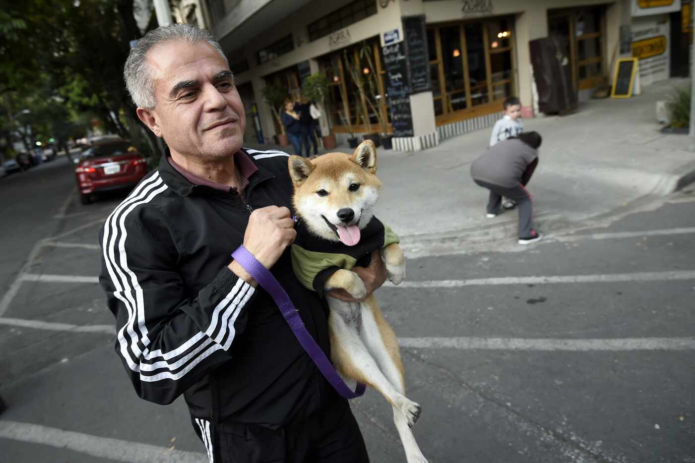 A man carrying his dog walks to the streets as he evacuates a building in Mexico City during...