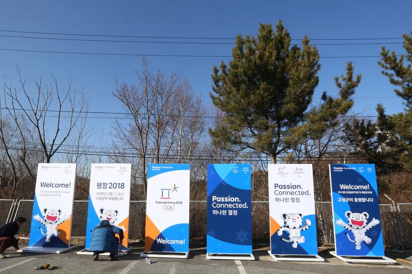 Workers install posters showing the 2018 Pyeongchang Winter Olympic mascot at the...