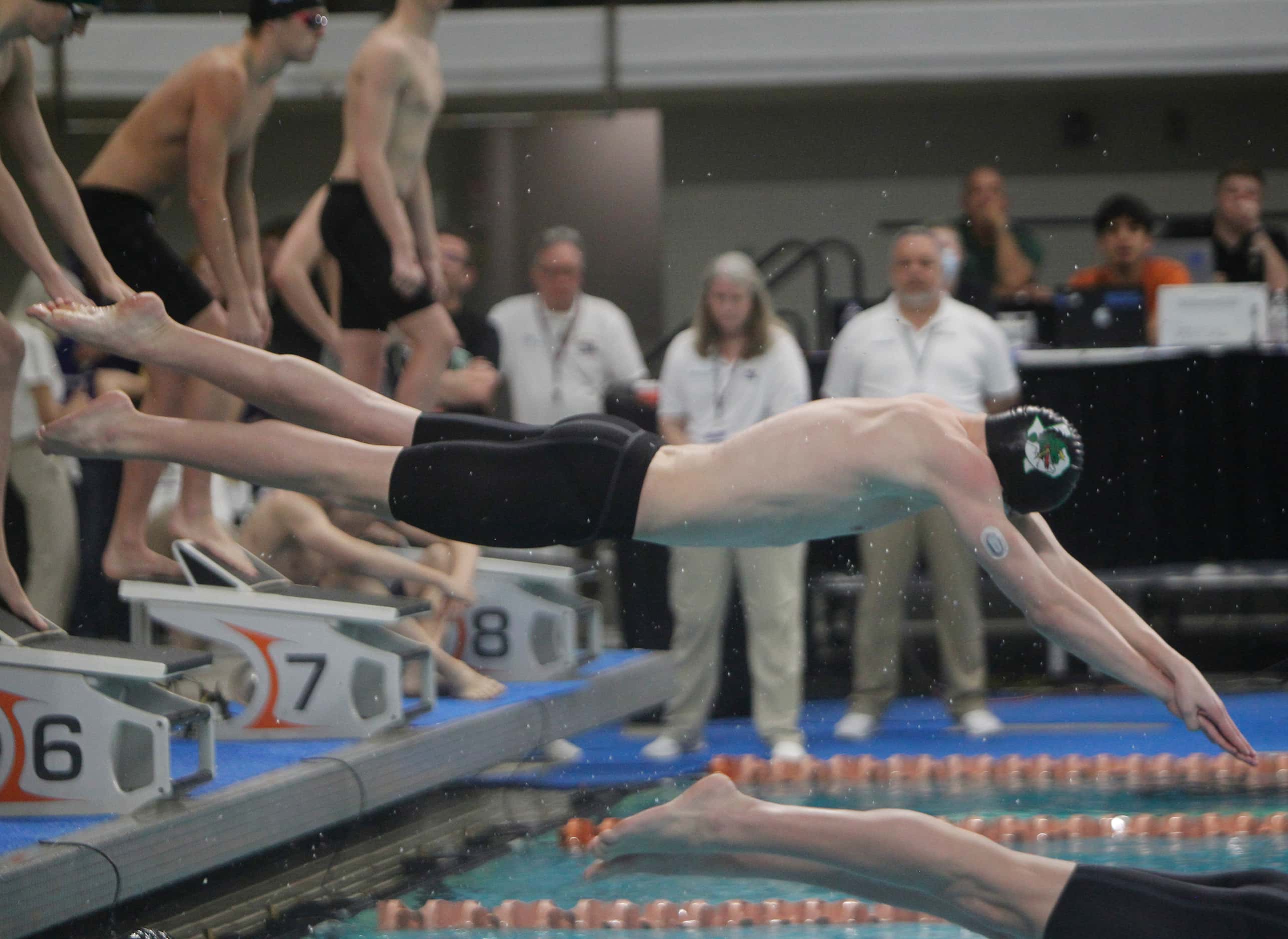 A member of the Southlake Carroll Boys 400 Yard Freestyle Relay team leaps into the pool to...