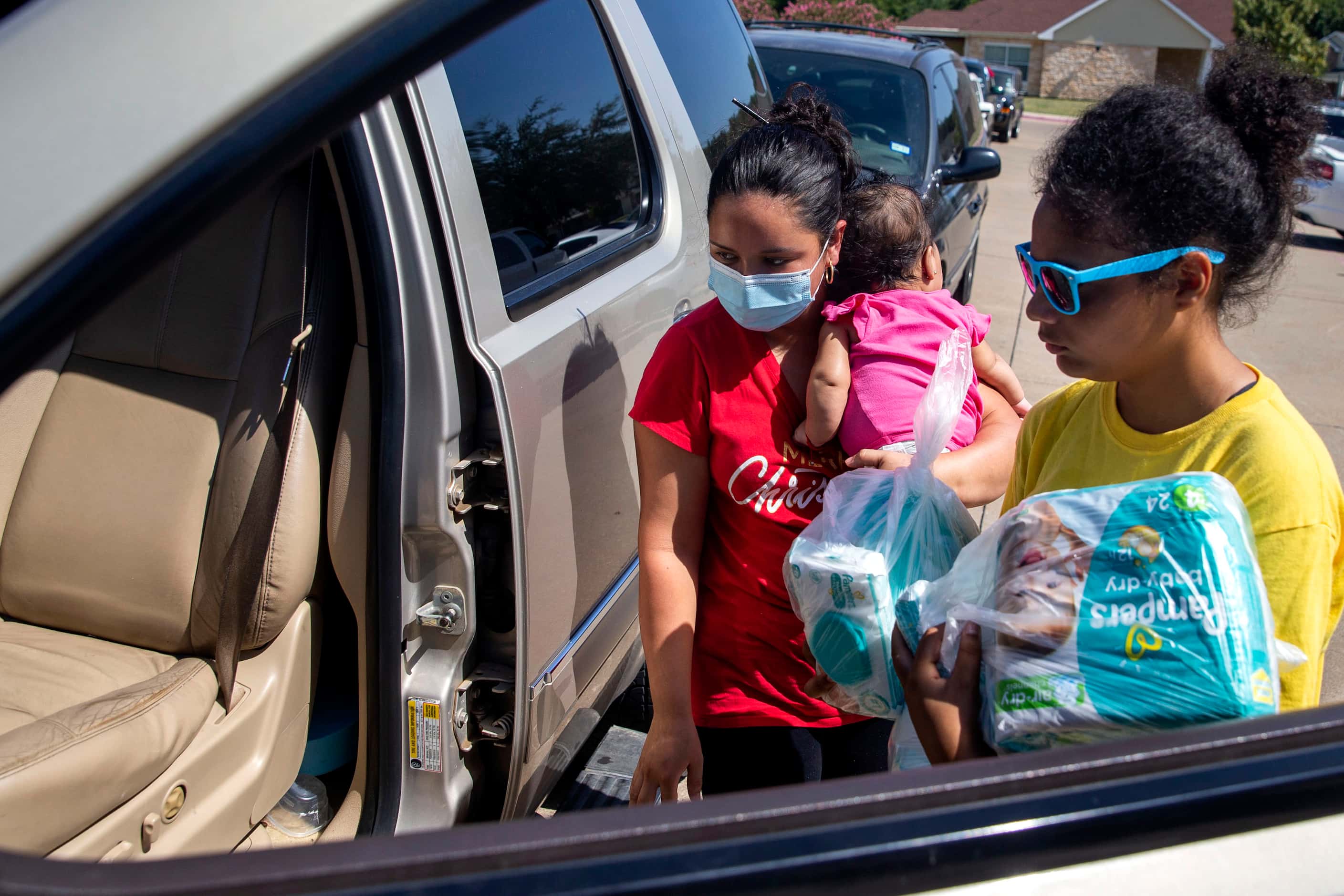 Volunteer Harmony Cornelius (right), 12, carries diapers for Zulema Quintanilla and her...