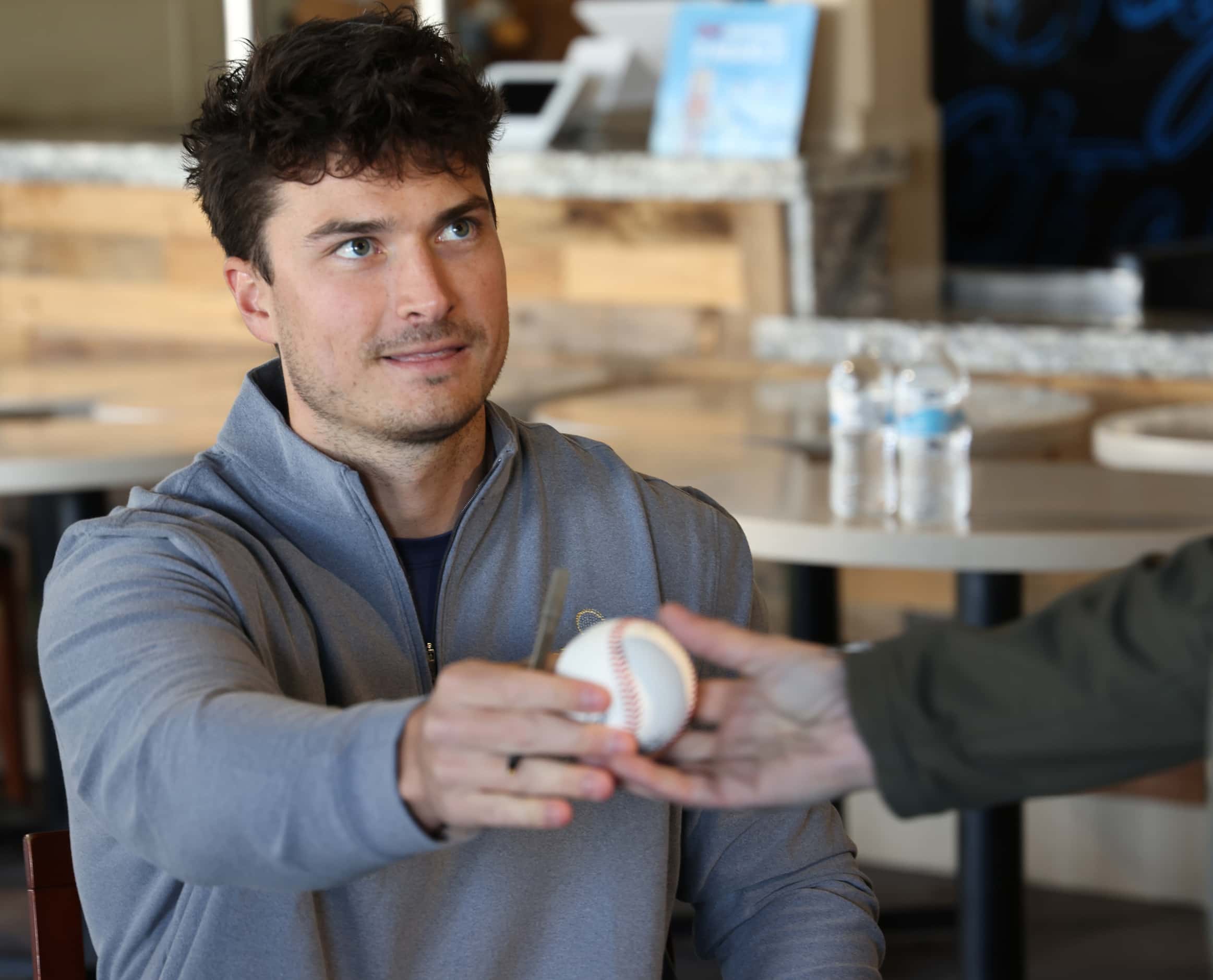 Justin Foscue autographs a baseball for a Rangers fan. Foscue, a right handed pitcher, is...