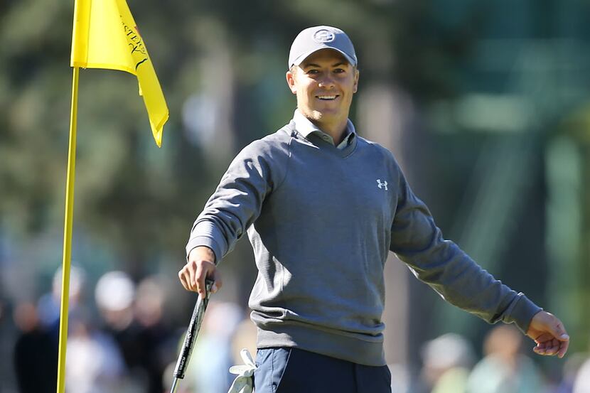 Masters defending champion Jordan Spieth smiles while putting on the third hole during a...