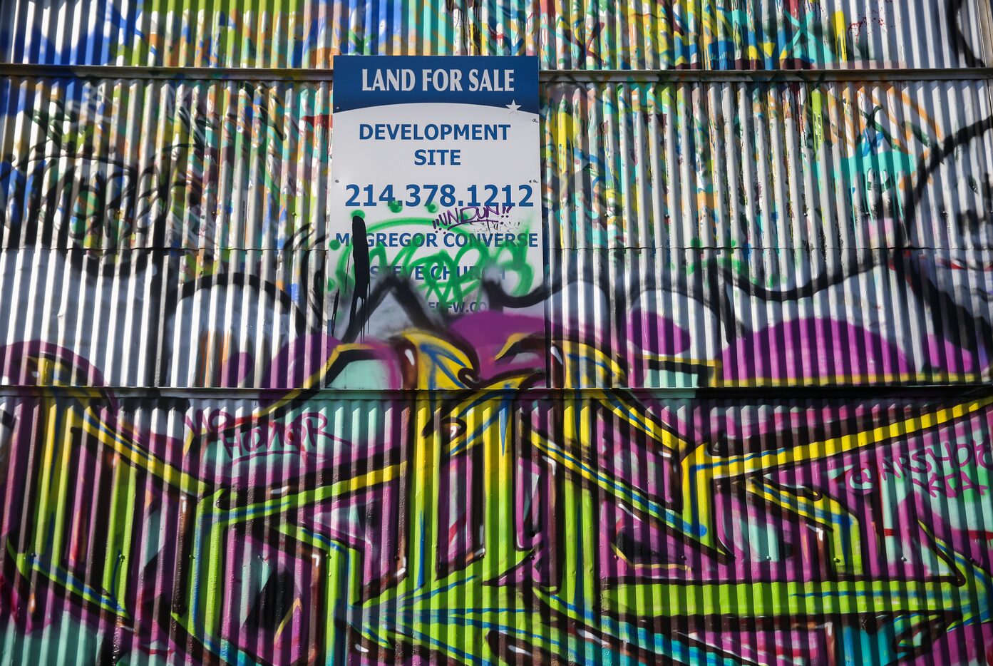 A for-sale sign is partially covered in graffiti at Fabrication Yard in West Dallas.