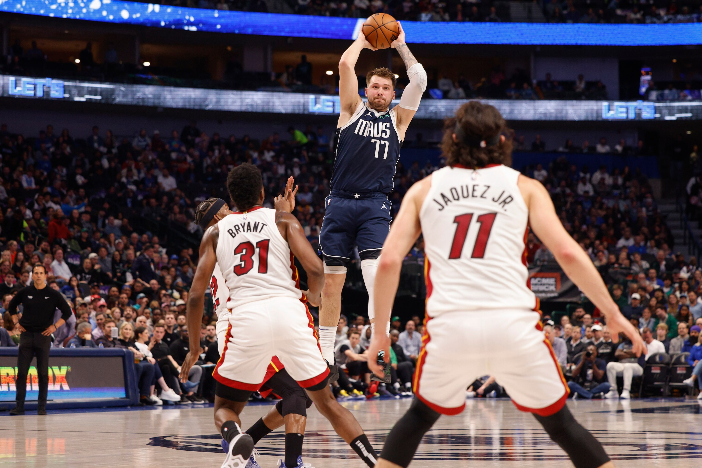 Dallas Mavericks guard Luka Doncic (77) makes a leaping pass over Miami Heat center Thomas...