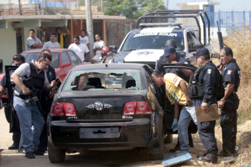 Mexican police examined a car containing a corpse and a human head in Acapulco on Jan. 20....