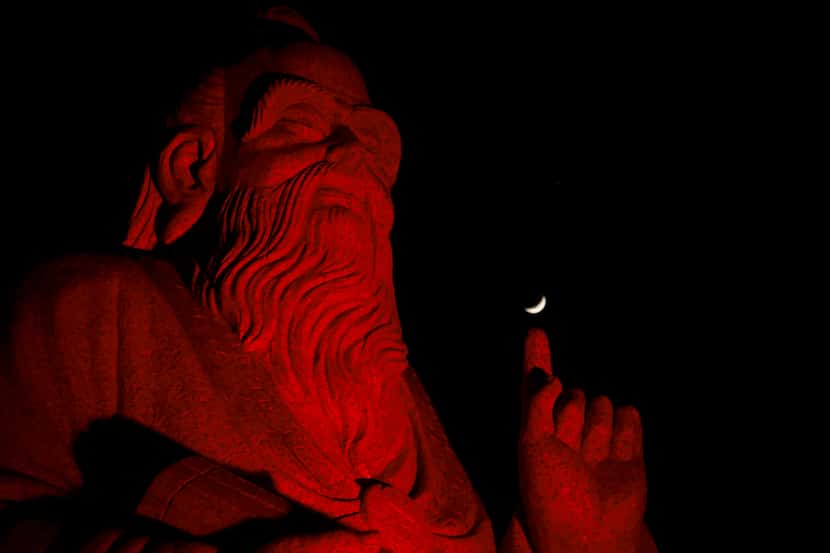 The moon floats above a statue of Chinese Philosopher Laozi, at DFW China Town, Wednesday,...