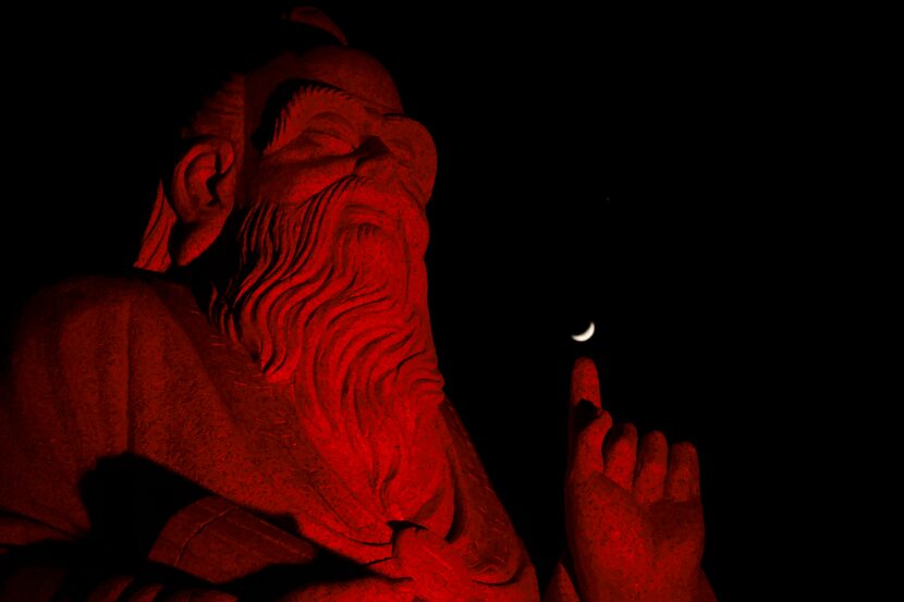 The moon floats above a statue of Chinese Philosopher Laozi, at DFW China Town, Wednesday,...