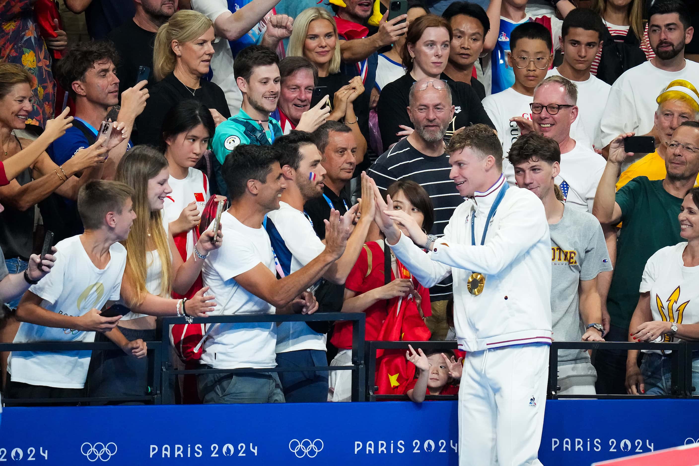 Leon Marchand of France celebrates with the crowd after winning the men’s 200-meter...