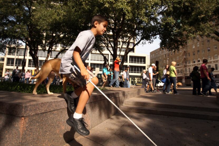With his white walking cane and buddy dog in tow, Zach Thibodeaux jumps off a wall in...