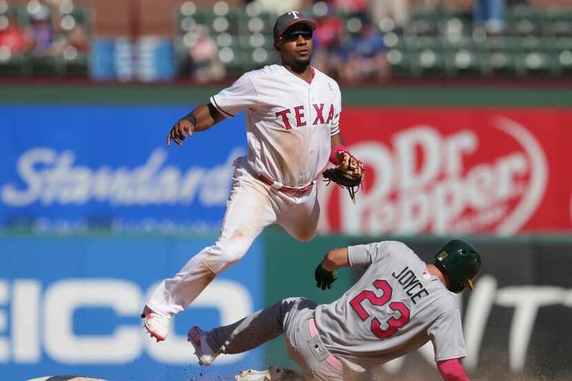 Elvis Andreus, paracorto de los Rangers de Texas, brinca al lanzar la pelota a primera base...