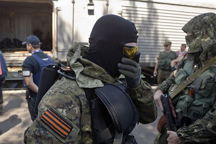 A pro-Russian rebel covers his nose due to the smell of decomposing bodies Monday in Torez,...