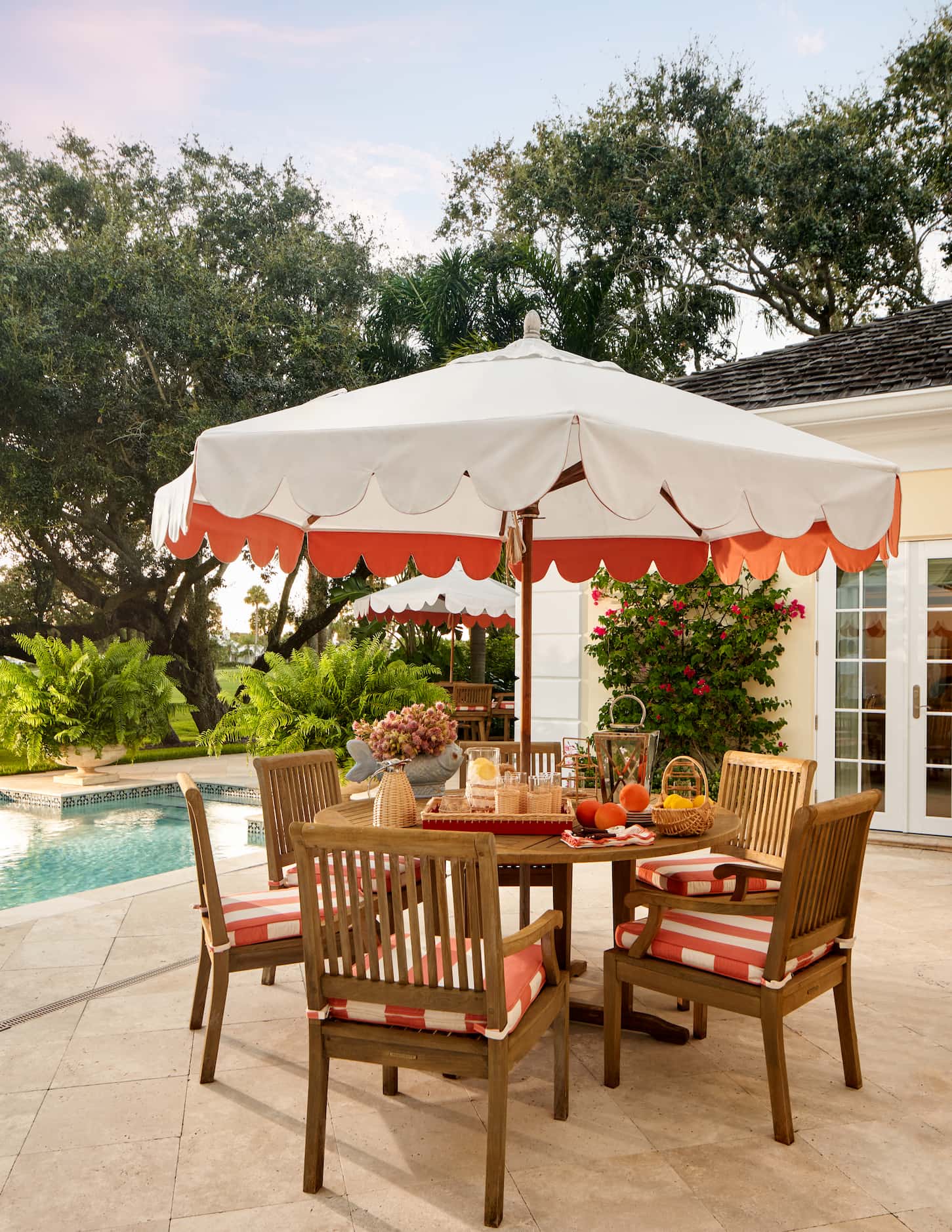 Wooden outdoor table with orange and white umbrella and orange stripe cushions on the chair